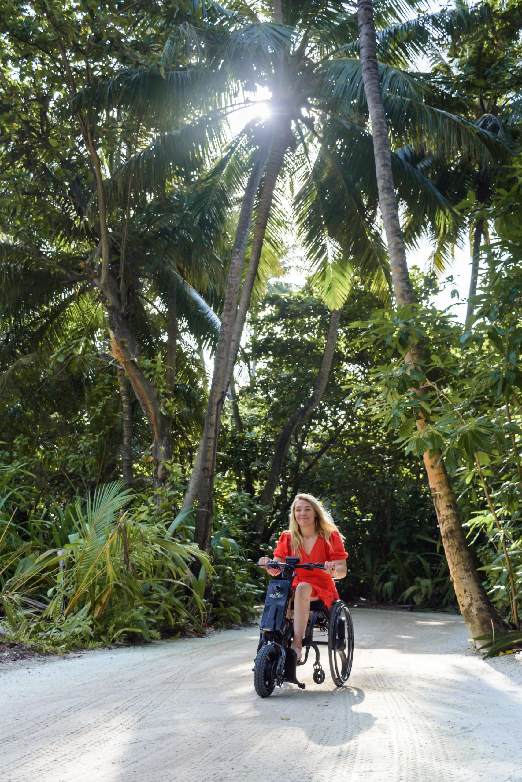 Sophie Morgan con su handbike eléctrico Batec Mini 2 por el camino de arena de playa en la jungla de las Maldivas en el resort Amilla Fussi.