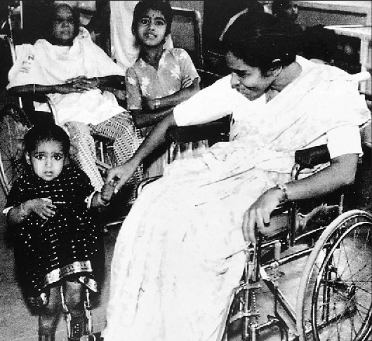 Mary Verghese cirujana en silla de ruedas junto a una paciente en la India.