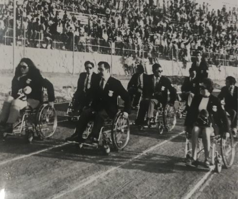 María Carmen Riu y Rita Granada desfilando en silla de ruedas junto a todo el equipo paralímpico español en las paralimpiadas de Tel Aviv (Israel) de 1968.