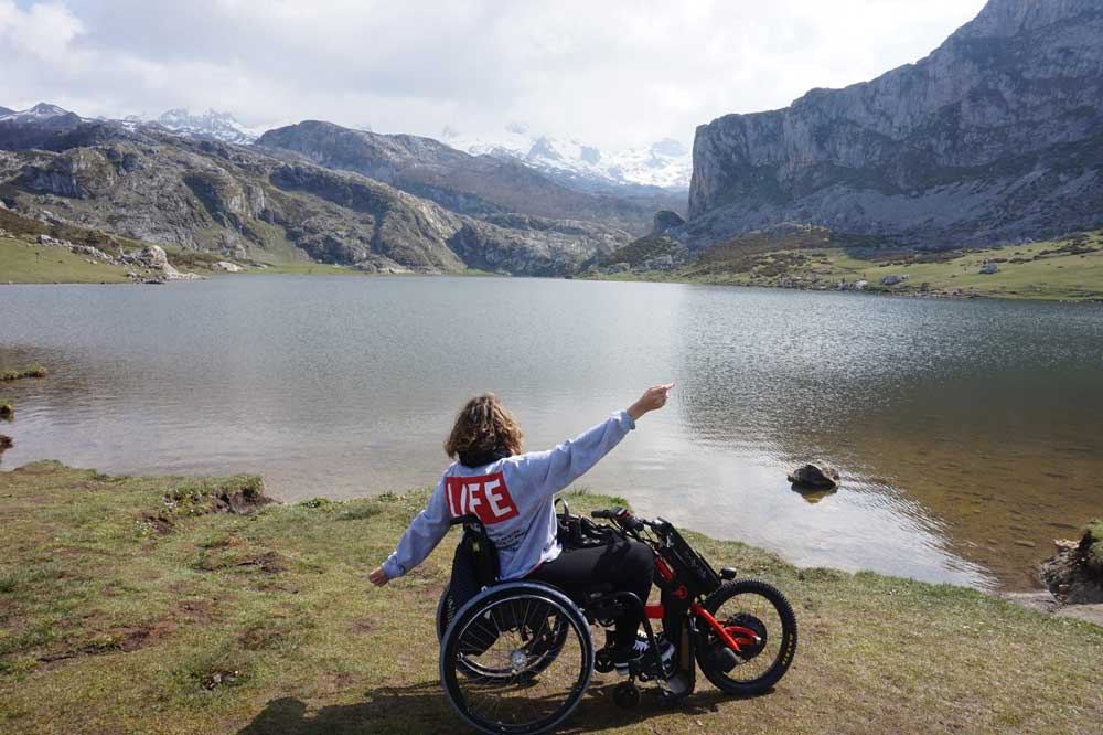 Chica en silla de ruedas con un handbike Batec eléctrico disfrutando de la naturaleza. De silla manual a silla de ruedas eléctrica.