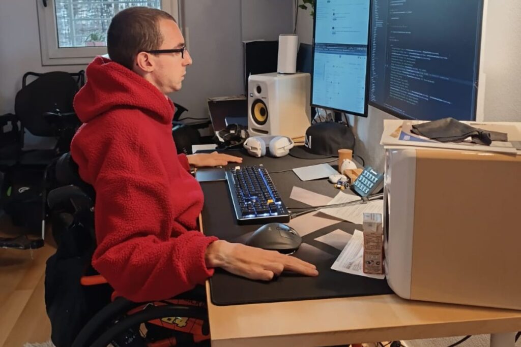 Chico tetrapléjico trabajando en su oficina con ratón trackball y teclado mecánico.