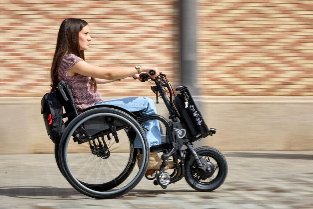 Chica en silla de ruedas paseando con un handbike acoplable